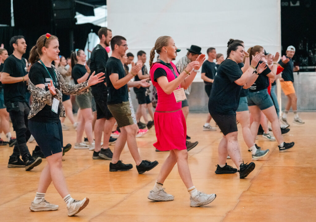 En gjeng som danse linedance på dansegulvet i storteltet.