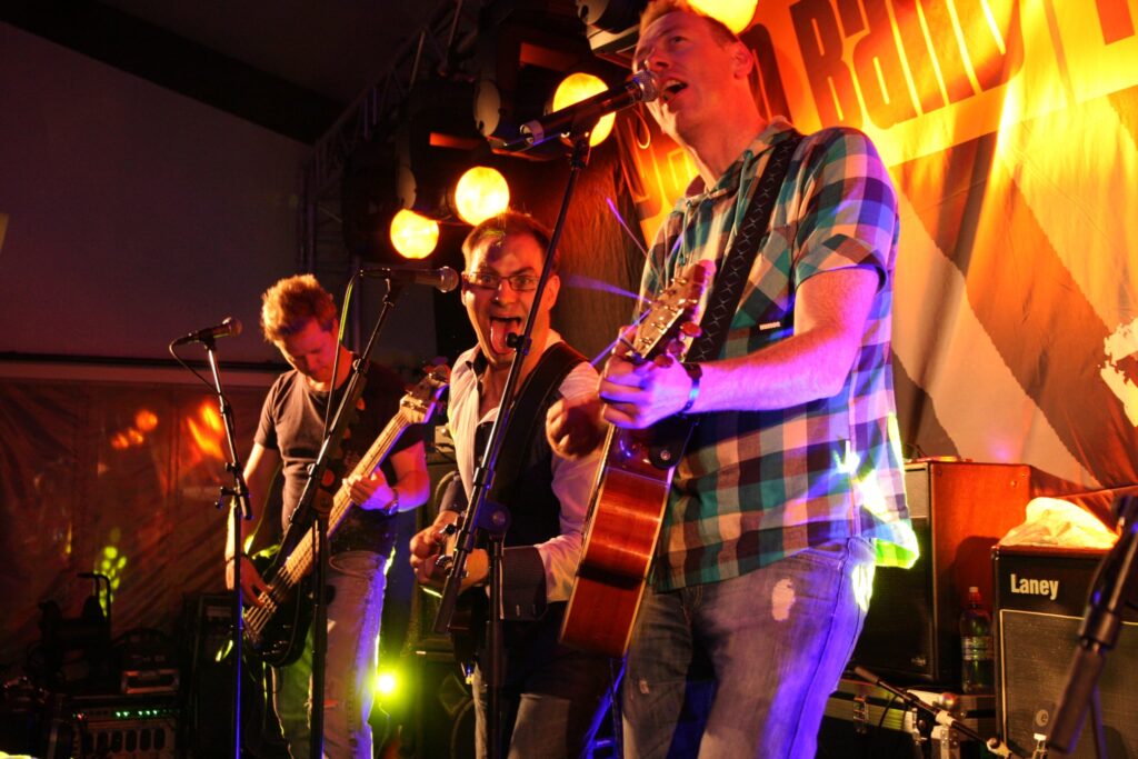 Bilde av bandet Tommy og Tigeren. Gitaristen ser i kamera med åpen munn og tunga ut.